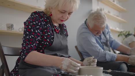 Three-elderly-people-work-on-a-potter's-wheel-in-slow-motion